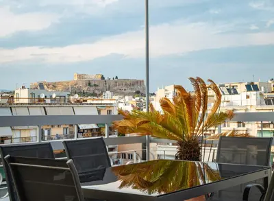 a table and chairs on a balcony with a palm tree at KASO - Vresthenis - Acropolis View in Athens