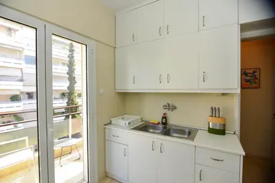a kitchen with white cabinets and a sink and a window at Athens stylish apt 2 min walk to the beach , tram in Athens