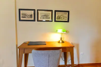 a desk with a lamp and pictures on the wall at Athens stylish apt 2 min walk to the beach , tram in Athens