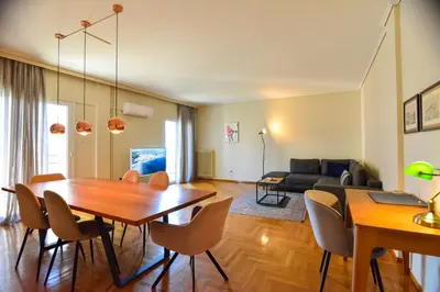 a dining room and living room with a table and chairs at Athens stylish apt 2 min walk to the beach , tram in Athens