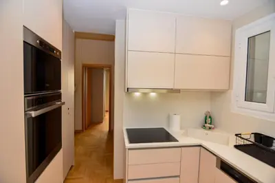 a kitchen with white cabinets and a black appliance at Athens centre top floor stylish 2 min walk metro in Athens