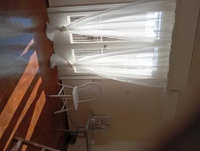 a window with a white curtain in a room at 4 Single beds room 5' from metro in Athens