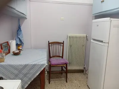 a kitchen with a table and a chair and a refrigerator at 4 Single beds room 5' from metro in Athens