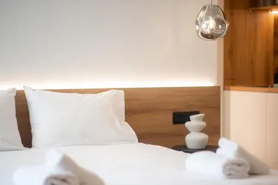 a bed with white pillows and a vase on a table at Megaro Luxury Suite 11 in Syntagma in Athens