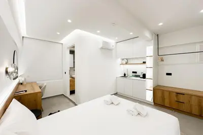 a white room with two beds and a kitchen at Megaro Luxury Suite 7 in Syntagma in Athens
