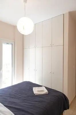 a bedroom with a large bed with white cabinets at Airport city center in Spáta
