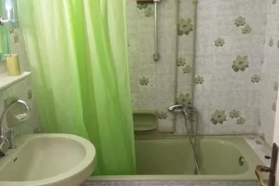 a bathroom with a green shower curtain and a tub at Comfortable Apartment in the Center of Piraeus in Piraeus