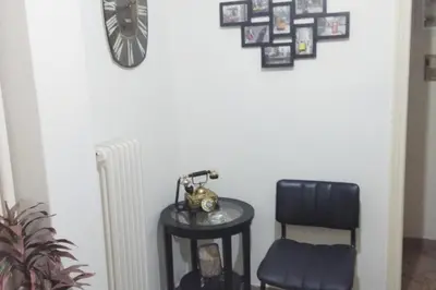 a table with a chair and a clock on a wall at Comfortable Apartment in the Center of Piraeus in Piraeus