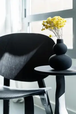 a black chair and a table with a vase with yellow flowers at ATELIER 64 , Monastiraki Apartments & Suites in Athens