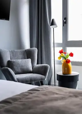 a bedroom with a chair and a vase with red flowers at ATELIER 64 , Monastiraki Apartments & Suites in Athens