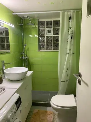 a green bathroom with a toilet and a sink at Aegean Light Flat near Metro in Athens