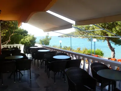 a row of tables and chairs on a balcony with the ocean at Liberty II in Agia Marina Aegina