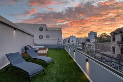 a balcony with a view of the city at sunset at The Industrial Loft - Private Rooftop & Jacuzzi in Athens