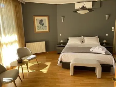 a bedroom with a large bed and a chair at Elegant, villa with pool in Athens Riviera in Athens