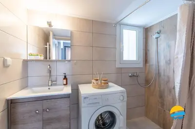 a bathroom with a washing machine and a sink at Pame Rentals - 2BD Modern Home Steps from Pasalimani in Piraeus