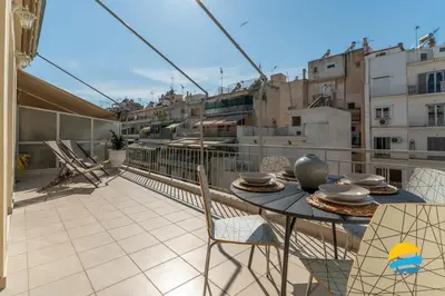a balcony with a table and chairs on a roof at Pame Rentals - 2BD Modern Home Steps from Pasalimani in Piraeus