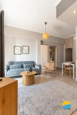 a living room with a blue couch and a table at Pame Rentals - 2BD Modern Home Steps from Pasalimani in Piraeus