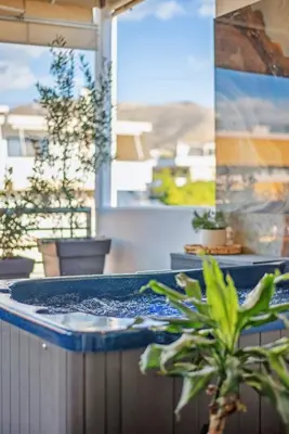 a hot tub on a patio with a potted plant at One-Bedroom Jacuzzi Glyfada in Athens