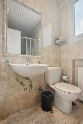 a bathroom with a sink and a toilet and a mirror at One-Bedroom Jacuzzi Glyfada in Athens
