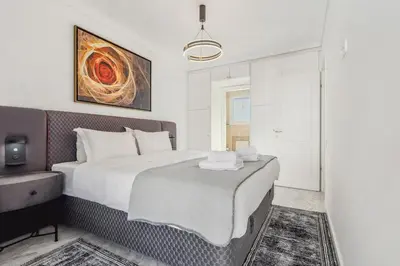 a bedroom with a large white bed and a mirror at One-Bedroom Jacuzzi Glyfada in Athens