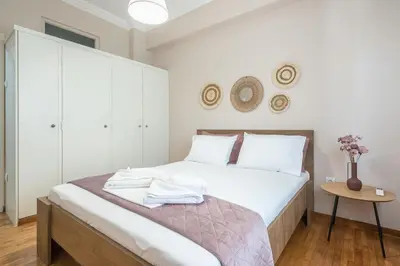 a bedroom with a bed with white sheets and a table at Ble Elia Karyatis Suite in Athens