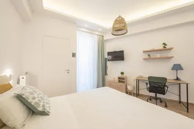 a bedroom with a white bed and a desk at Ble Elia Karyatis Suite in Athens