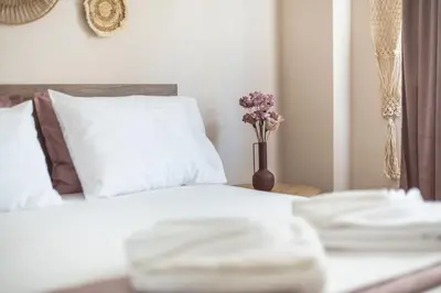 a bed with white sheets and a vase of flowers on a table at Ble Elia Karyatis Suite in Athens