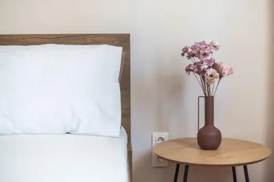 a vase with flowers on a table next to a bed at Ble Elia Karyatis Suite in Athens