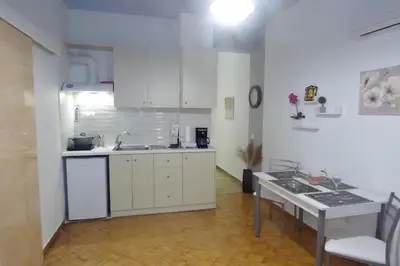 a kitchen with white cabinets and a table at Panormou Studio metro station by MPS in Athens