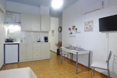 a kitchen with white cabinets and a table and a sink at Panormou Studio metro station by MPS in Athens