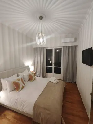 a bedroom with a large white bed with a chandelier at Pangrati Varnava -2 Bedroom Flat in Athens