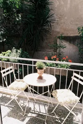 a table and chairs with a potted plant on a balcony at Newly Renovated Apartment in a Lush Green Neighborhood in Central Athens in Athens