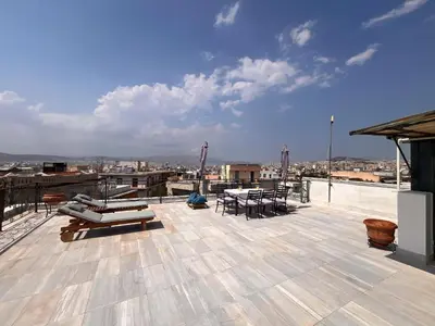 a deck with chairs and tables on a roof at Thiseio Villa Acropolis View in Athens