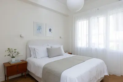a white bedroom with a bed and a window at Athenian Vintage Apartment in Athens