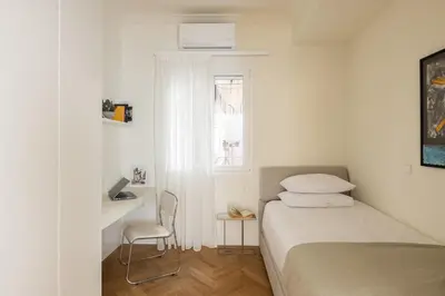 a small white bedroom with a bed and a window at Athenian Vintage Apartment in Athens