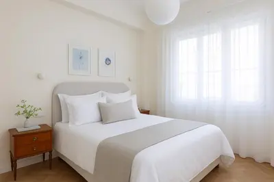 a white bedroom with a large white bed with white pillows at Athenian Vintage Apartment in Athens