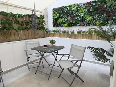 a table and chairs in a patio with a vertical garden at Smart Athens Stay, Studio Near Acropolis & Metro in Athens
