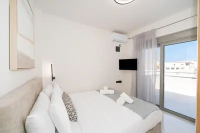 a white bedroom with a large bed and a window at Acropolis View - Stylish City Penthouse with Large Terrace in Athens