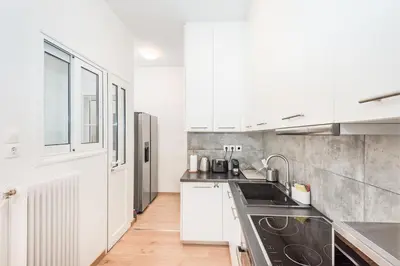 a kitchen with white cabinets and a black sink at Spacious apt with 2 beds and 2 baths in Pagrati in Athens