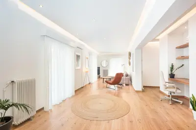 a living room with white walls and a wooden floor at Spacious apt with 2 beds and 2 baths in Pagrati in Athens