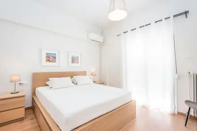 a white bedroom with a white bed and a window at Spacious apt with 2 beds and 2 baths in Pagrati in Athens