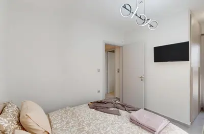 a white bedroom with a bed and a flat screen tv at Κ2 Varkiza Seaside Residences in Vari