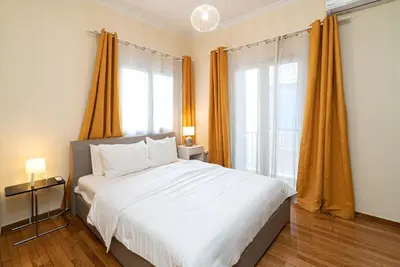 a bedroom with a large white bed with orange curtains at Casa Del Guerriero, Athens in Athens