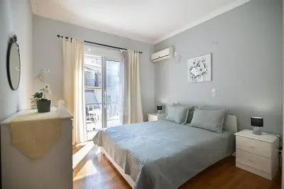 a white bedroom with a bed and a window at CitySoul Athens in Athens
