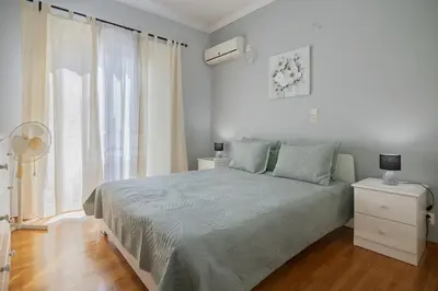 a white bedroom with a bed and a window at CitySoul Athens in Athens