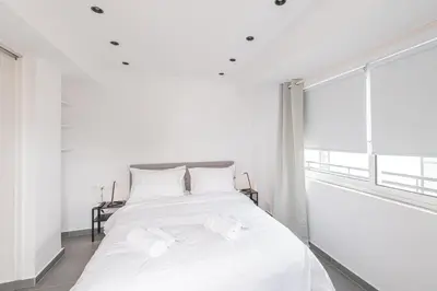 a bedroom with a white bed with white sheets and a window at South Metro Suite in Athens