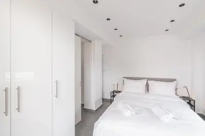 a white bedroom with a white bed with white pillows at South Metro Suite in Athens