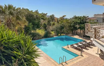 a large swimming pool with lounge chairs and trees at Gorgeous Home In Lagonisi With Wifi in Lagonissi
