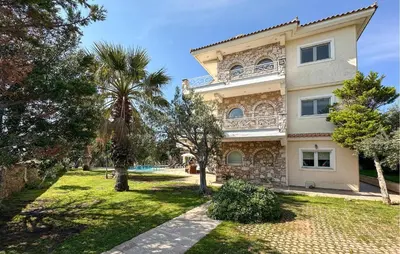 a large building with a palm tree in front of it at Gorgeous Home In Lagonisi With Wifi in Lagonissi