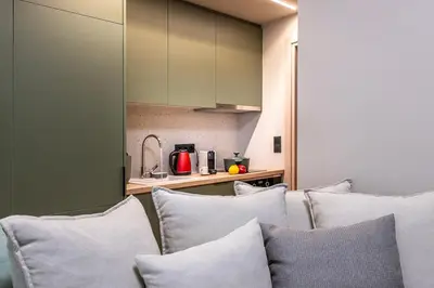 a living room with white pillows and a kitchen at Cozy 1BR with Balcony in Kipseli in Athens